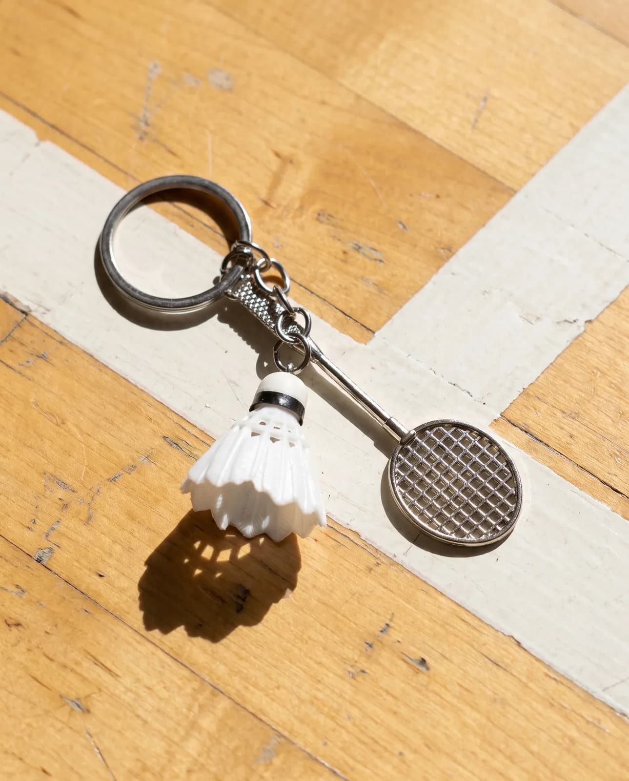 Badminton keyring on a sports hall floor by a court line
