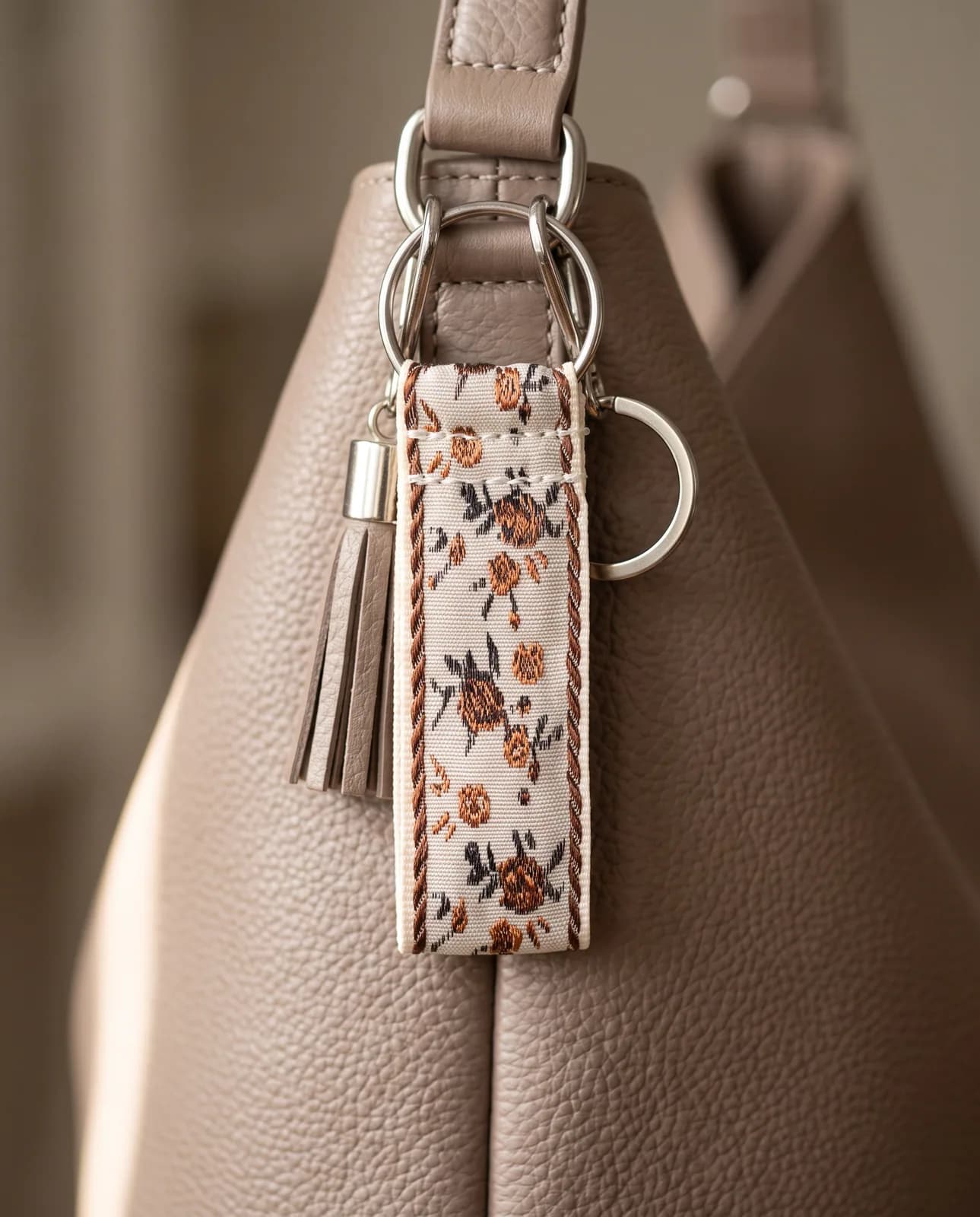 Ivory brocade key fob on a taupe leather handbag