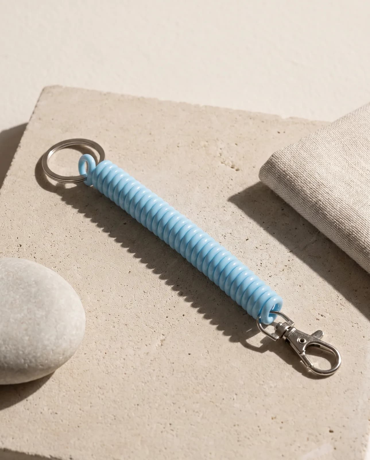 Sky blue coil keychain on pale concrete in hard light