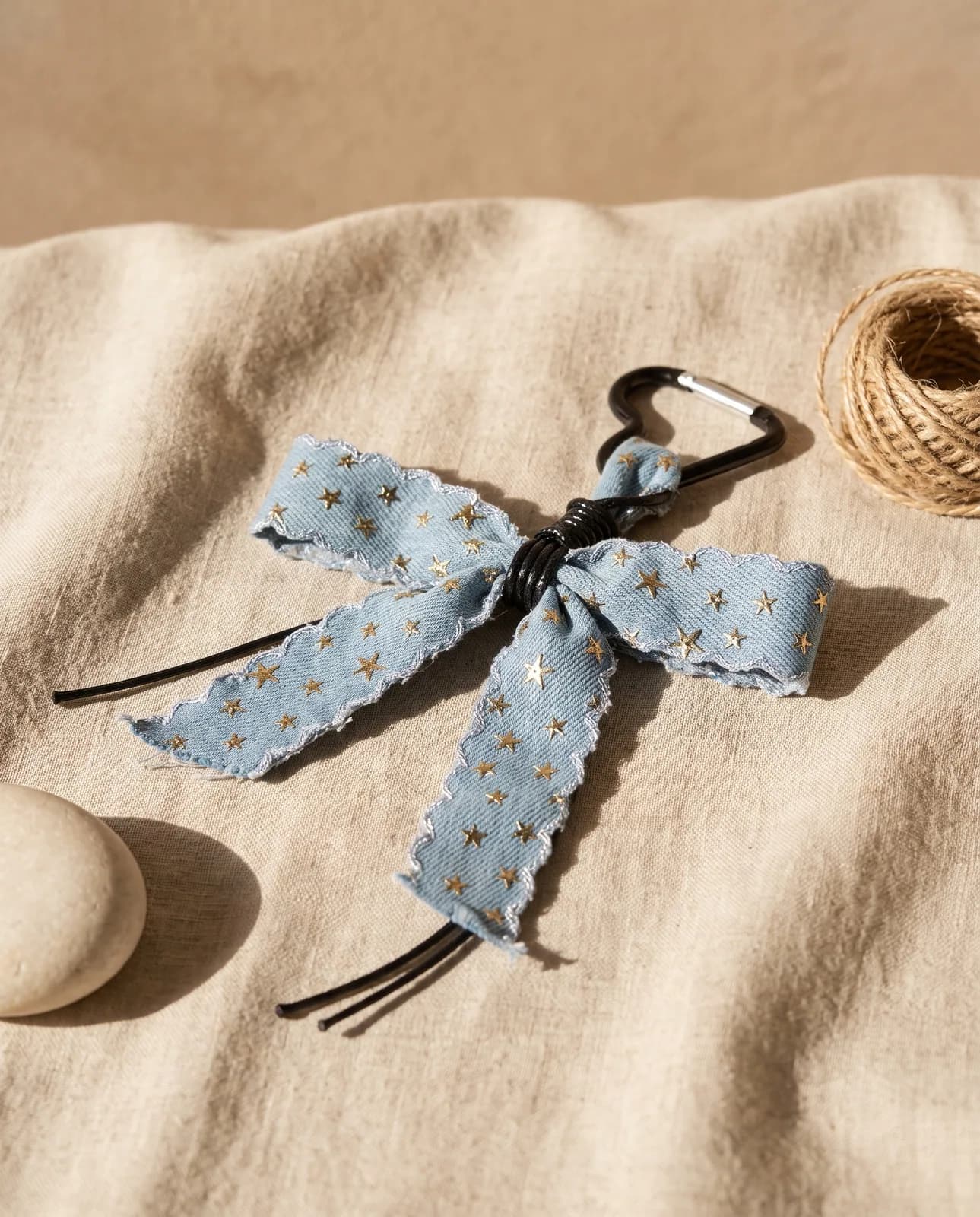 Denim star bow charm on oatmeal linen in hard light