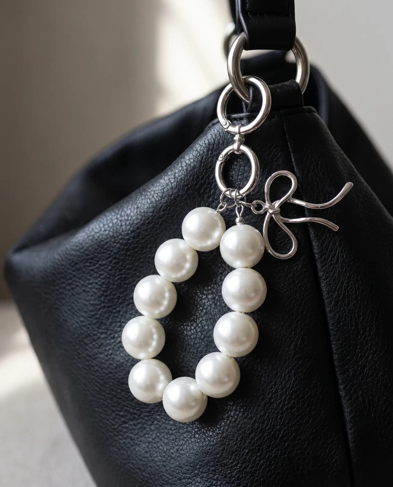 Pearl loop charm on a black leather handbag