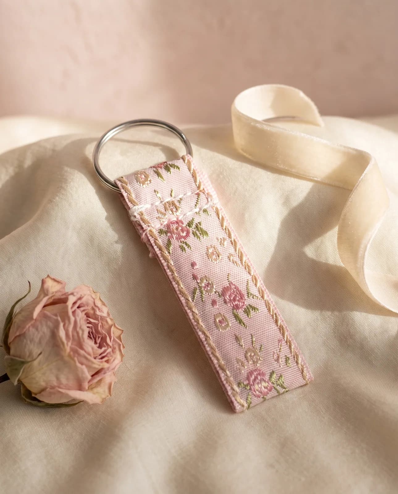 Rose brocade key fob on cream silk with a dried rose