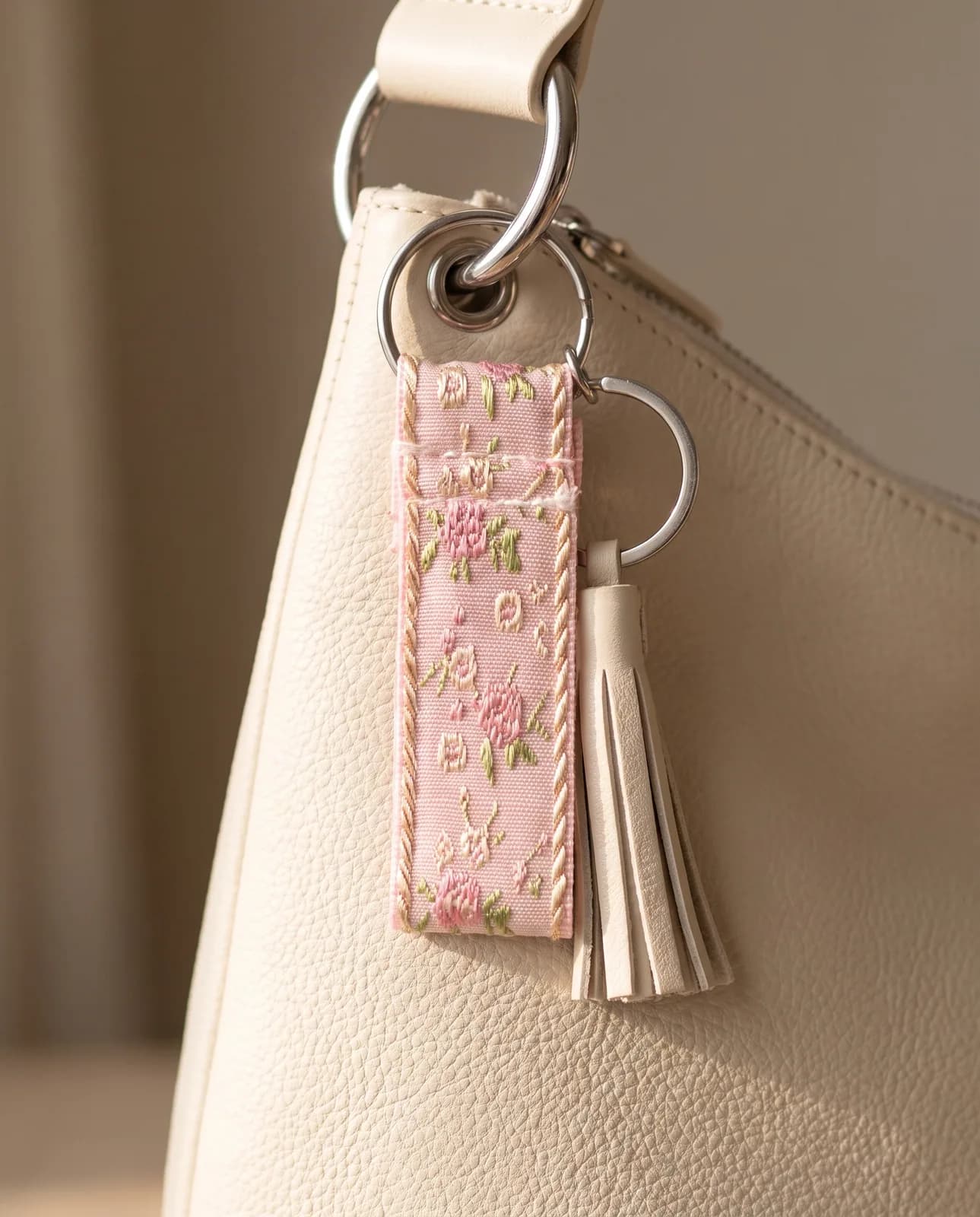 Rose brocade key fob on a cream leather handbag
