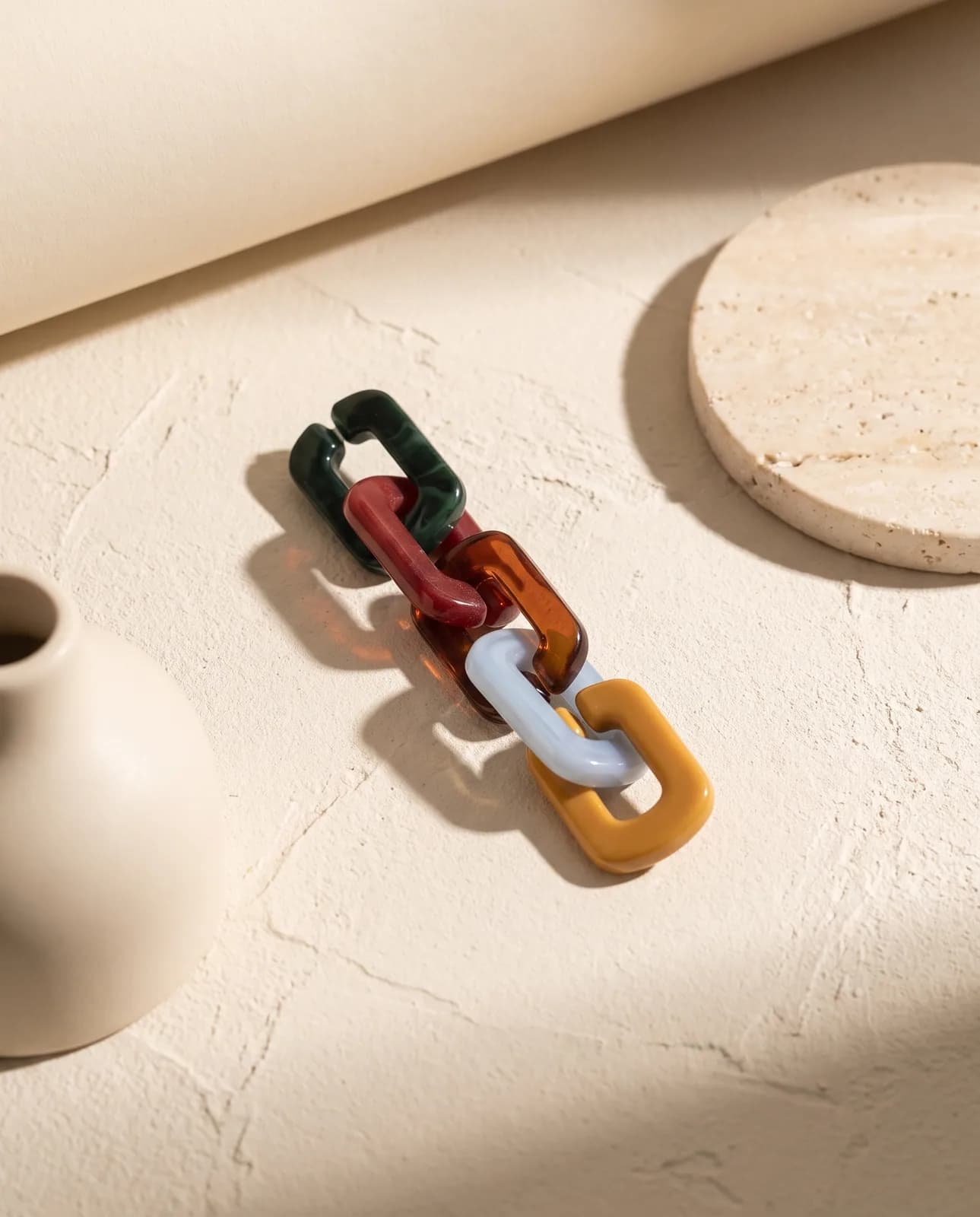 Resin chain charm on cream plaster in hard light