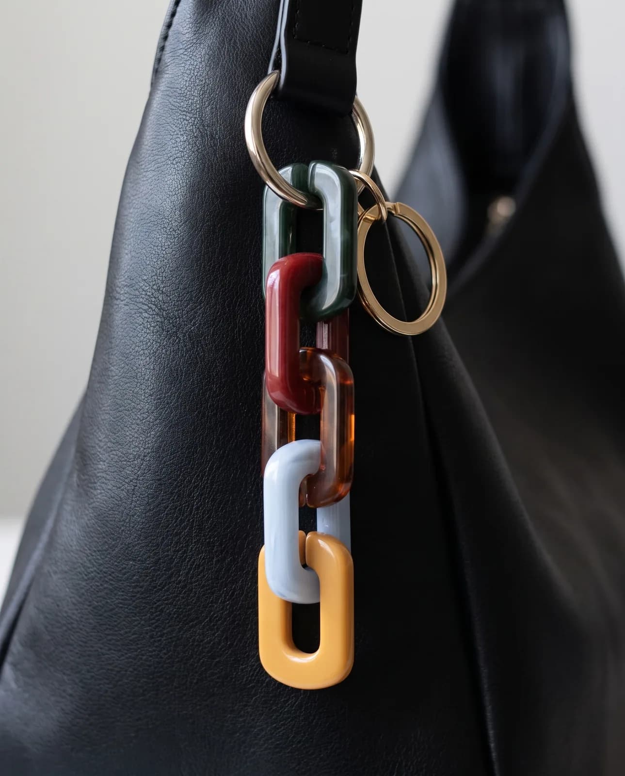 Resin chain charm on a black leather shoulder bag