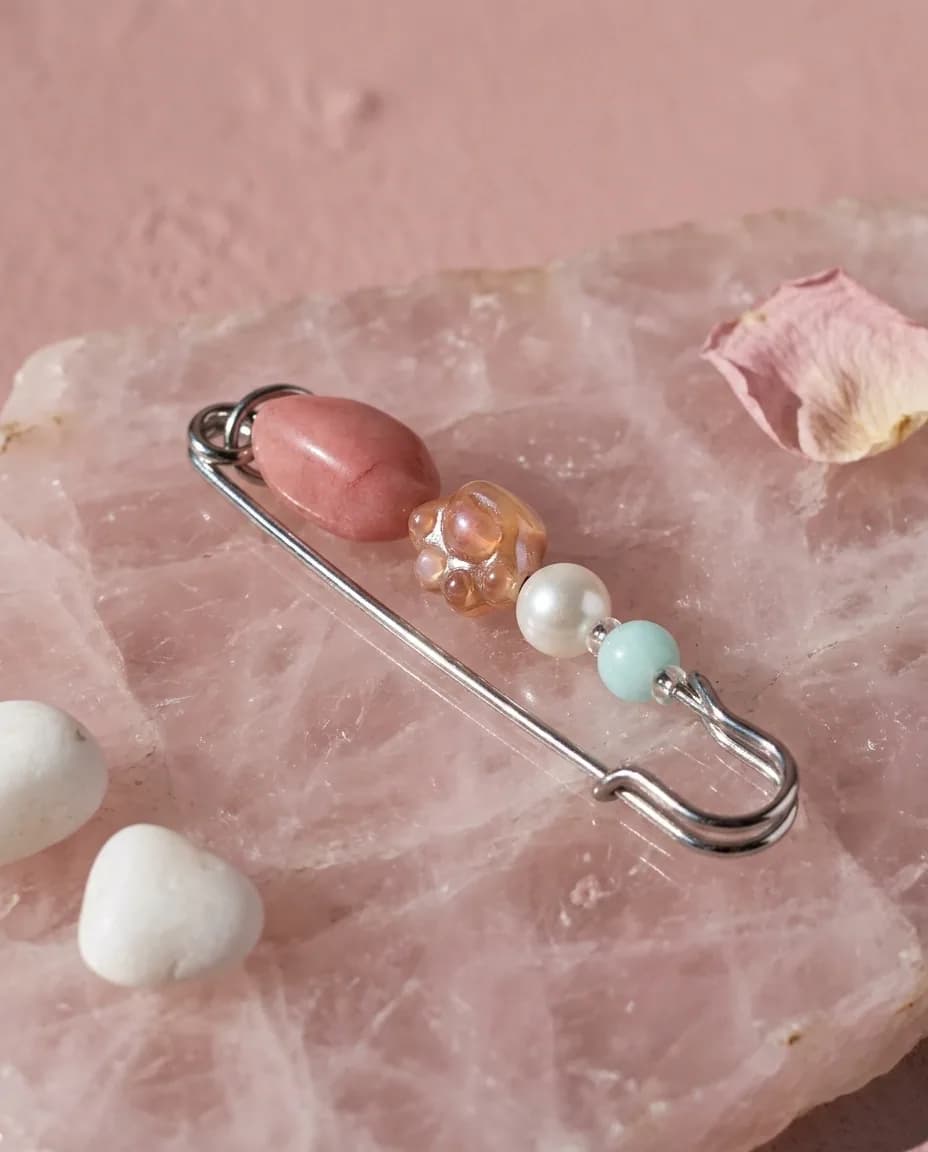 Rose quartz kilt pin on a rose quartz slab in daylight