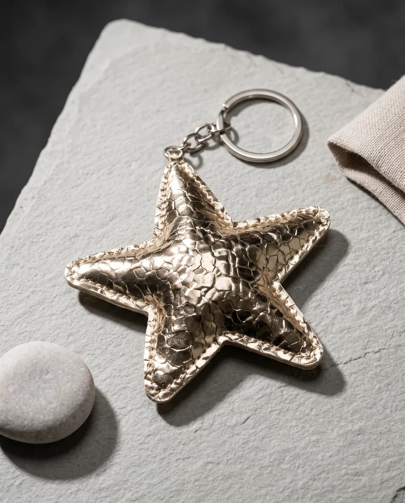 Metallic gold star keyring on grey slate
