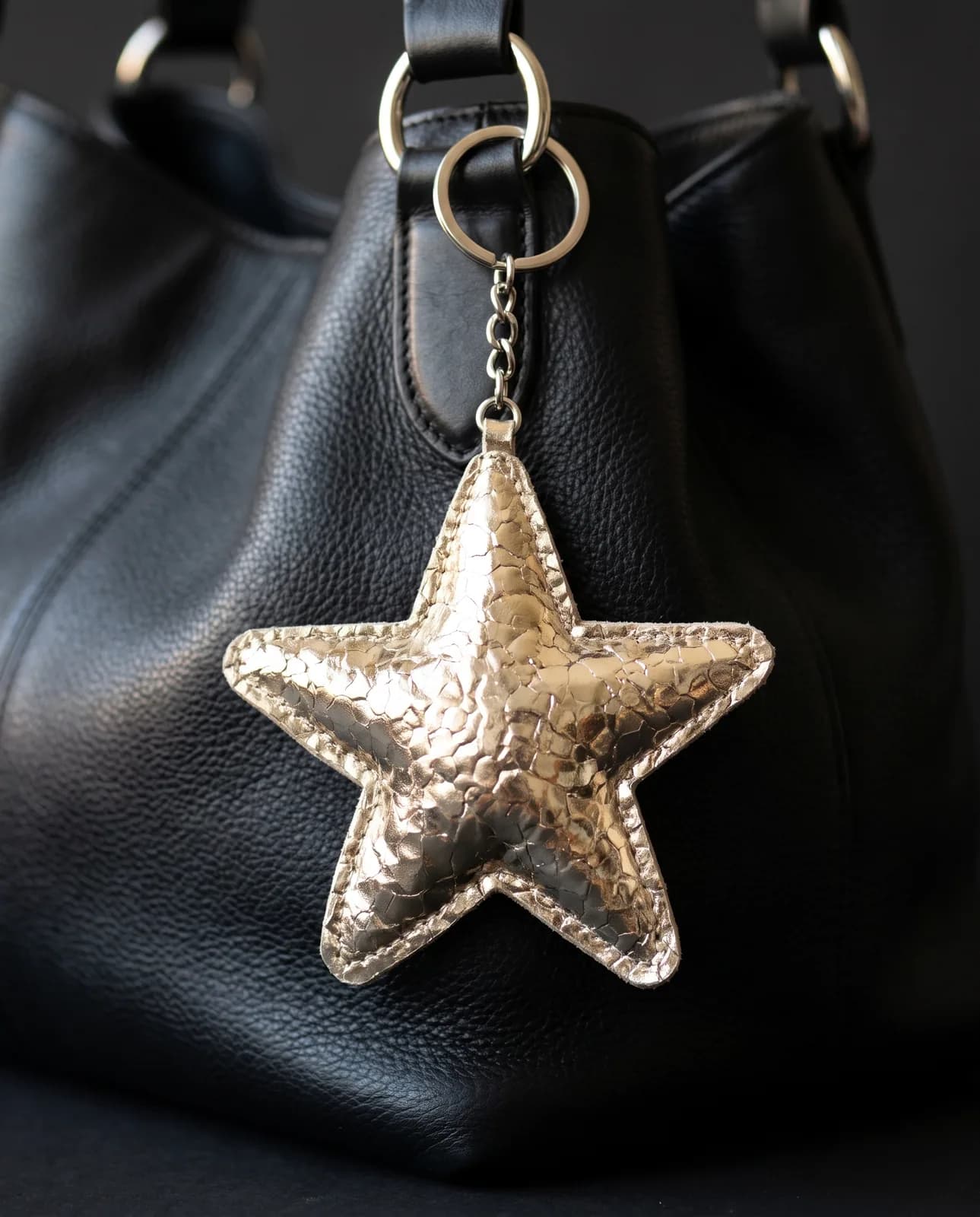 Metallic gold star keyring on a black leather handbag