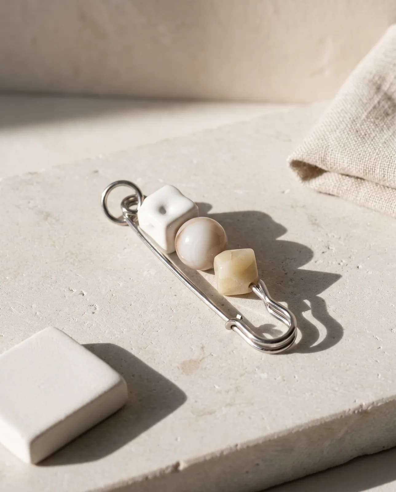 Neutral ceramic bead pin on pale limestone