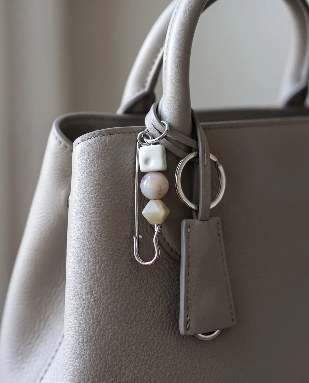Neutral ceramic bead pin on a stone grey leather handbag